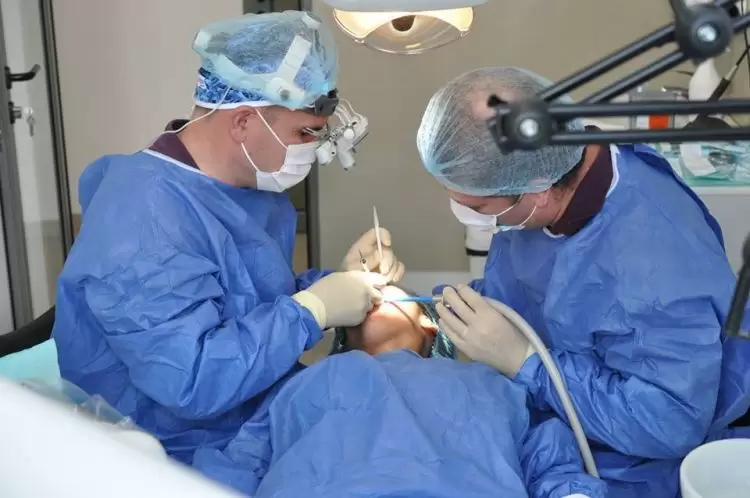 doi medici stomatologi efectuează o intervenție chirurgicală de inserare a implanturilor